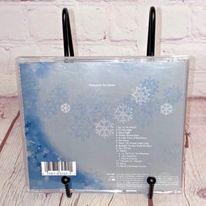 May include: A CD case with a blue and white snowflake design. The back of the case lists the songs on the CD, including "Joy to the World", "O Holy Night", and "Winter Wonderland".