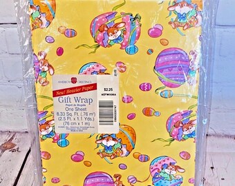 Puede incluir: Un papel de regalo amarillo con un patrón de conejos, huevos y diseños de temática de Pascua. El texto en el papel de regalo dice "New! Heavier Paper Gift Wrap Papel de Regalo One Sheet 8.33 Sq. Ft. (.76 m²) (2.5 Ft. x 1.1 Yds.) (76 cm x 1 m) $2.25 AEFWOOSA".