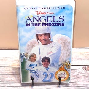May include: A VHS tape for the Disney movie "Angels in the Endzone" featuring Christopher Lloyd. The cover art shows a man with angel wings and football players. The title is in blue and yellow.