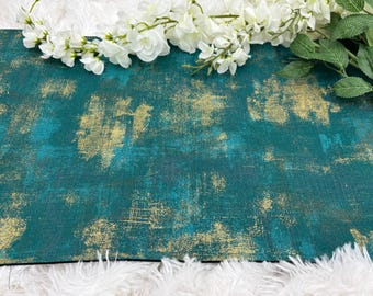 May include: A teal and gold abstract textured surface. The surface has a distressed look with gold accents over a teal base. White flowers and green leaves are arranged at the top of the surface.