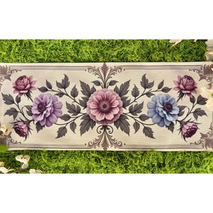 May include: Rectangular floral design featuring a cream background with a border. The design includes purple, pink, and blue flowers with gray leaves. The flowers are arranged symmetrically, with a central large flower and smaller ones on the sides.