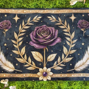 May include: A rectangular, dark blue decorative mat with a floral and celestial design. The mat features a large purple rose in the center, surrounded by gold-colored leaves and feathers. Stars and crystals are scattered across the background.