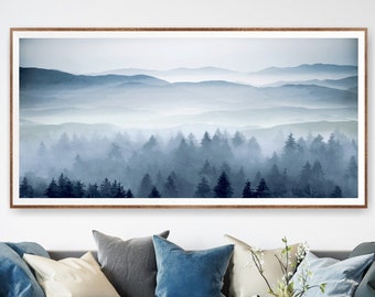 May include: A framed print of a misty forest scene with a blue and gray color palette. The print features a row of trees in the foreground with a series of rolling hills in the background.