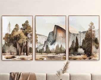 May include: Three framed landscape prints with watercolor-style scenery. The prints feature a mountain range, a forest, and a grove of trees. The prints are hung on a white wall above a beige sofa.