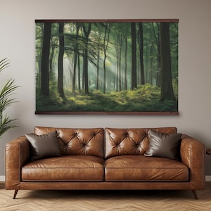 May include: A framed forest landscape print. The image depicts tall trees in a lush green forest with sunlight streaming through the canopy. The print is mounted on a dark brown wooden frame, hanging above a brown leather sofa.