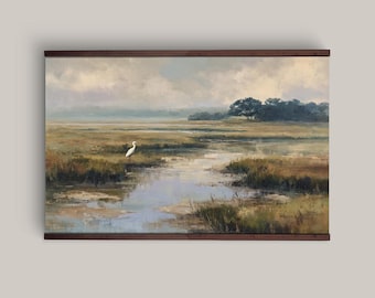 May include: A landscape painting in a dark brown frame depicting a marshland scene with a single white egret standing near a winding stream. The horizon features a line of dark green trees under a cloudy, muted sky with earthy tones.