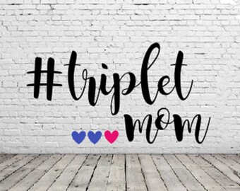 May include: A white brick wall with black text that reads "#triplet mom" with three hearts below the text. The hearts are blue and pink.