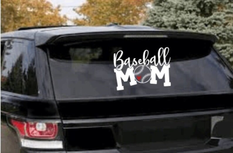 May include: White vinyl decal with the text "Baseball Mom" and a baseball with a red heart in the centre. The decal is on the back window of a black SUV.