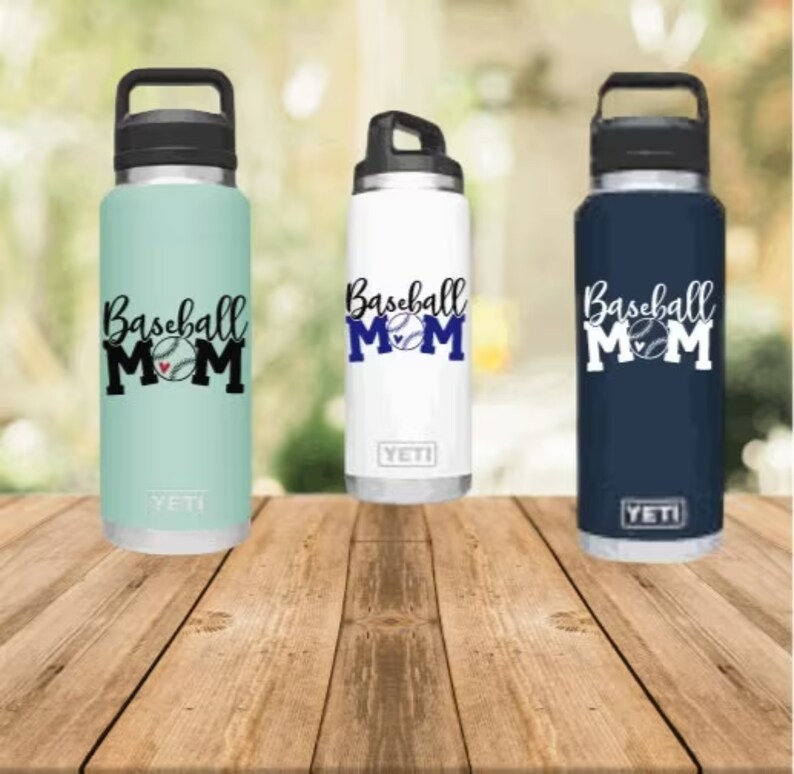 May include: Three stainless steel water bottles with black lids and handles. Each bottle has a different colour: light blue, white, and navy blue. The bottles have a baseball and the text "Baseball Mom" printed on them.