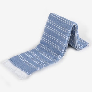 May include: A blue and white patterned towel with fringe. The towel is folded in half and has a white background with blue squares.