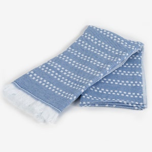 May include: A blue and white patterned towel with a fringe border. The towel is folded in half and has a geometric design.