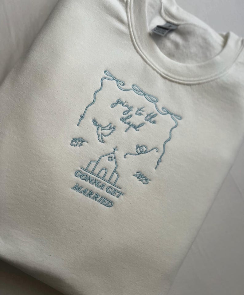 May include: White sweatshirt with blue embroidered text that reads "going to the chapel gonna get married" with a church, dove, and hearts.