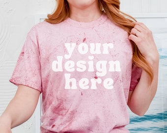 Könnte beinhalten: Ein pinkfarbenes Batik-T-Shirt mit dem Text "your design here" in Weiß. Das Shirt wird von einer Person getragen, die auf dem Boden sitzt und die Beine übereinandergeschlagen hat.
