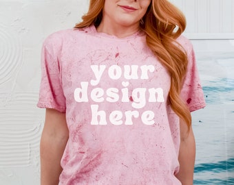May include: A pink tie-dye t-shirt with the text "your design here" in white. The shirt is worn by a person with long red hair and blue jeans.