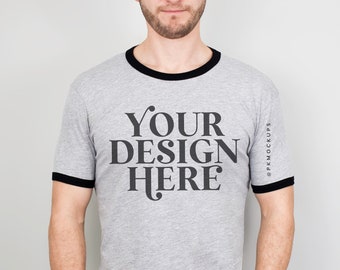 May include: A gray t-shirt with a black ringer and the text "YOUR DESIGN HERE" printed on the front.