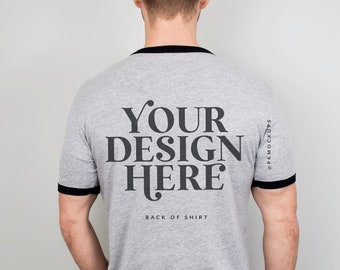 May include: A heather grey t-shirt with a black ribbed crew neck and black trim on the sleeves. The back of the shirt has the text "YOUR DESIGN HERE" and "BACK OF SHIRT" printed in black.