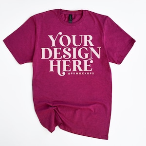 Puede incluir: Una camiseta de color granate con un diseño blanco que dice "YOUR DESIGN HERE" y "@PKMOCKUPS" debajo.