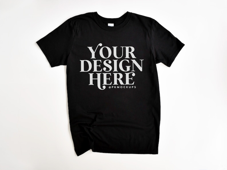 May include: Black t-shirt with the text "YOUR DESIGN HERE" in white lettering and the text "@PKMOCKUPS" in smaller white lettering below.