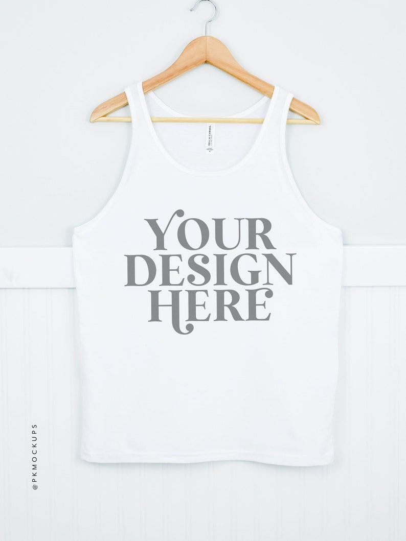 May include: White tank top with a wooden hanger. The tank top has the text "YOUR DESIGN HERE" printed on the front in gray.