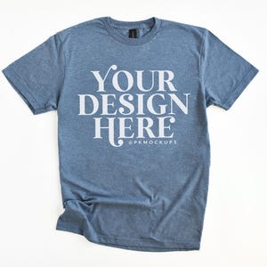 May include: A blue t-shirt with the text "YOUR DESIGN HERE" in white lettering. The shirt is made of a soft, comfortable material and has a relaxed fit.