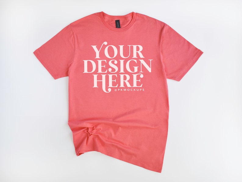 May include: A coral colored t-shirt with the text "YOUR DESIGN HERE" in white. The text is centered on the shirt and is surrounded by a white border.