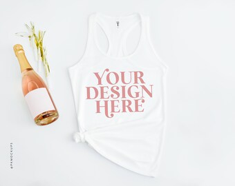 May include: White tank top with a racerback design. The tank top is laying flat on a white surface. The text "YOUR DESIGN HERE" is printed in pink on the front of the tank top.