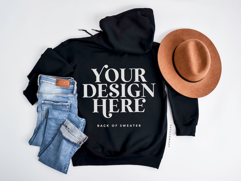 May include: Black hoodie with the text "YOUR DESIGN HERE" and the words "BACK OF SWEATER" below it. Light blue jeans and a brown hat are also in the image.