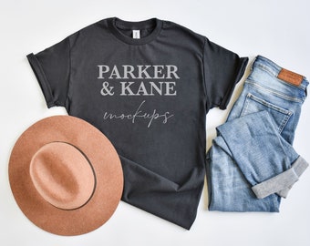 May include: A black t-shirt with the text "PARKER & KANE mockups" in gray lettering. The t-shirt is laid flat on a white surface with a brown hat and blue jeans.