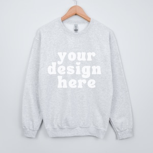 Può includere: Una felpa grigia melange con la scritta "your design here" stampata in bianco sul davanti.