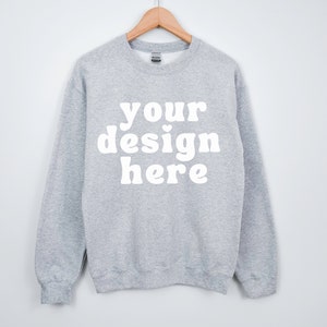 Peut inclure: Un sweat-shirt gris chiné avec le texte "your design here" en blanc.