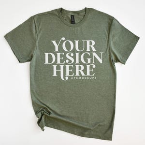 May include: A green t-shirt with the text "YOUR DESIGN HERE" in white lettering. The shirt is made of a soft, comfortable material and has a relaxed fit.