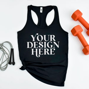 May include: Black racerback tank top with the text "YOUR DESIGN HERE" printed on the front. The tank top is laying flat on a white surface with a jump rope and two orange dumbbells.
