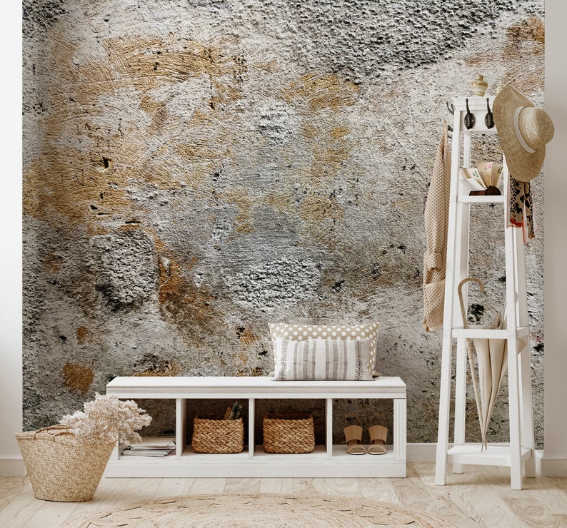 Puede incluir: Una entrada de tonos neutros con un fondo de pared texturizado. Se ve un banco blanco con cestas de mimbre y un perchero con un sombrero y un paraguas. Una alfombra redonda y una cesta con flores secas completan la decoraci&oacute;n.