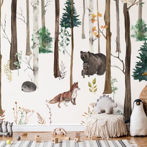 May include: A wall mural featuring a watercolor forest scene with birch and pine trees, a brown bear with a cub, a fox, and a hedgehog. In the foreground, there is a woven basket shaped like a penguin, a plush penguin, and a small dinosaur toy.