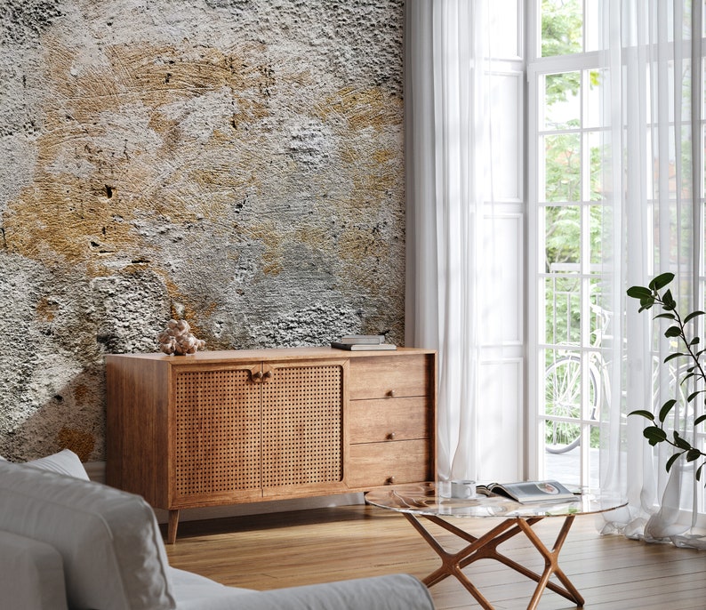 Puede incluir: Un aparador de madera con un panel de puerta tejido y dos cajones. El mueble est&aacute; colocado contra una pared texturizada con una mezcla de tonos grises, marrones y blancos. Tambi&eacute;n se ve una mesa de centro con tapa de cristal y cortinas blancas.
