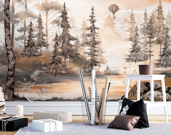 Puede incluir: Un mural de pared que muestra un paisaje forestal en acuarela con pinos altos, un río tranquilo y un globo aerostático en un cielo cálido de tonos naranja y marrón. La escena incluye una cesta de alambre con rollos de papel y dos cojines.