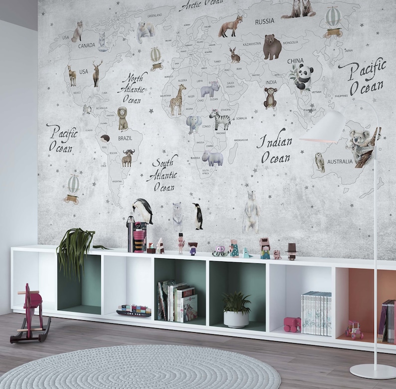 Puede incluir: Un gran mural de pared que muestra un mapa del mundo con contornos grises, oc&eacute;anos etiquetados y varios animales ilustrados colocados en los continentes. El mapa incluye texto para oc&eacute;anos y pa&iacute;ses sobre un fondo gris texturizado.