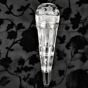 May include: A clear glass vase with a flared, ribbed body and a rounded top. The top features etched floral designs and a textured band. The vase is approximately 10 inches tall.