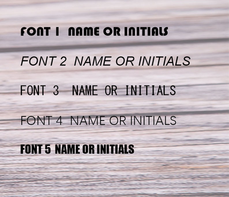 May include: Image showcasing five different font styles labeled Font 1 through Font 5. Each font is accompanied by the text "NAME OR INITIALS" in black, against a light wood grain background. The fonts vary in style, offering a selection for personalization.