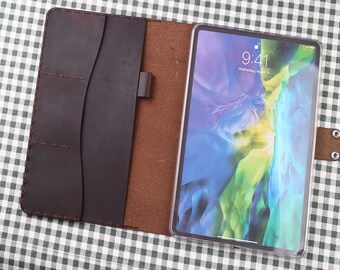 May include: A brown leather folio case with a flap closure and a built-in pocket. The case is open and a tablet with a bright, colorful screen is inside. The tablet screen shows the time as 9:41.