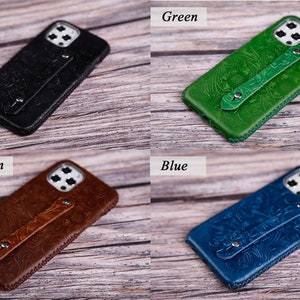 May include: Four leather phone cases in black, green, light brown, and blue. Each case features a floral embossed design and a hand strap. The cases are displayed on a wooden surface.