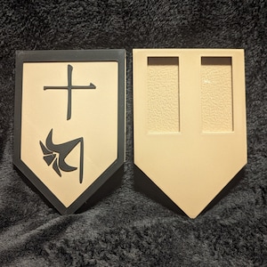 May include: Two wooden shields, one with a black border and a black and white symbol, the other with two empty slots. The symbol on the shield is a stylized cross with a stylized arrow pointing down.