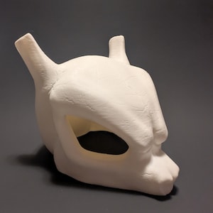 May include: White ceramic mask with a skeletal design. The mask has two horns on top and a large eye hole in the center.