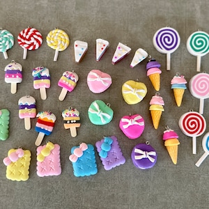 May include: A collection of 24 colorful clay charms featuring various sweet treats, including lollipops, ice cream cones, cupcakes, and cookies. The charms are all handmade and have a whimsical, playful design.