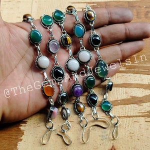 May include: Five silver bracelets with different colored gemstones. The bracelets have a hook clasp. The gemstones include green, blue, pink, white, orange, purple, black, and tiger's eye.