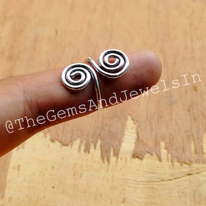 May include: Silver spiral ring with two connected spirals. The ring is worn on a finger.