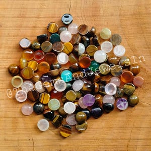 Puede incluir: Surtido de piedras preciosas redondas en cabujón de varios colores, incluyendo ojo de tigre, amatista, cuarzo rosa y cornalina. Las piedras preciosas miden aproximadamente 10 mm de diámetro y son ideales para la elaboración de joyas.
