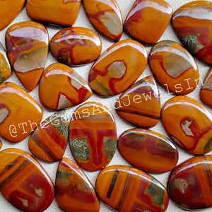 Puede incluir: Una colección de piedras preciosas pulidas, de forma ovalada y de lágrima. Las piedras presentan una mezcla de colores cálidos, incluyendo tonos de naranja, rojo y marrón, con patrones y vetas únicos. Las piedras preciosas son probablemente para la fabricación de joyas o coleccionar.