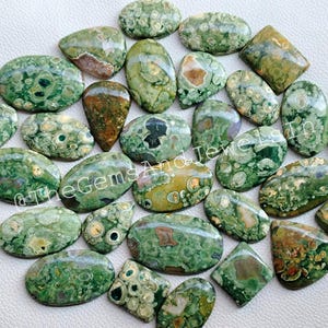 May include: A collection of 20 green, brown, and white polished ocean jasper cabochons. The cabochons are oval, teardrop, and rectangular shapes. The stones have a unique pattern of green, brown, and white swirls and spots.