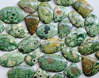 May include: A collection of 20 green, brown, and white polished ocean jasper cabochons. The cabochons are oval, teardrop, and rectangular shapes. The stones have a unique pattern of green, brown, and white swirls and spots.